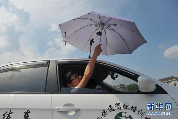 7月20日，在浙江省臨安市一家駕校內，一名學員在車頂架著遮陽傘的教練車內練習。