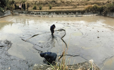 12月11日，陬市鎮青龍村連魚口組堆放工業廢料護壩的下游沉淀池內，施工人員將原本紅色的水排出，然后清淤。據涉事企業相關負責人介紹，清淤結束后，將請湖南省環境科學研究所重新規劃設計沉淀池。