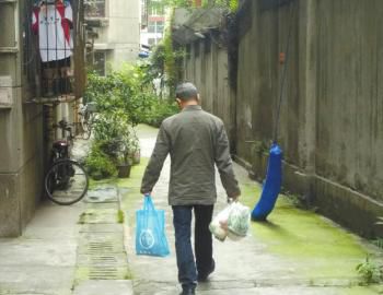 成都某中學外的小區內，一家長用中午空閑時間給住在這里的孩子買菜做飯。