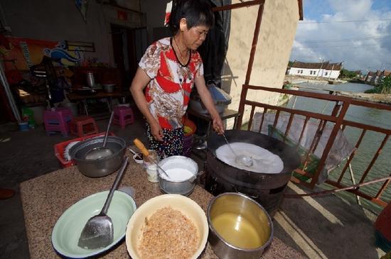 　5月27日，埭美村一位經營小吃店的村民在為游客做當地美食“鍋邊糊”