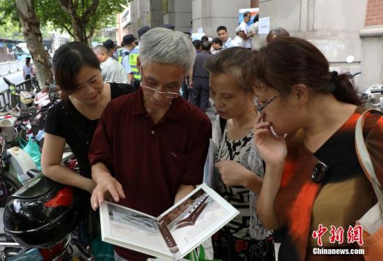 資料圖：幾位杭州市民欣賞已買到的“G20杭州峰會明信片”。 中新社記者 王剛 攝