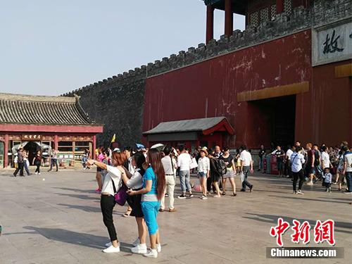 游客在故宮北門外用自拍桿合影。中新網(wǎng)記者 宋宇晟 攝