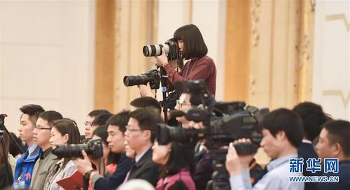 3月7日，一名女記者在十二屆全國人大五次會議江蘇代表團全體會議上采訪拍攝。在兩會會場內外，女代表、女委員、女工作人員、女記者在工作中盡職盡責，展現著自己的風采。 新華社記者陳曄華攝