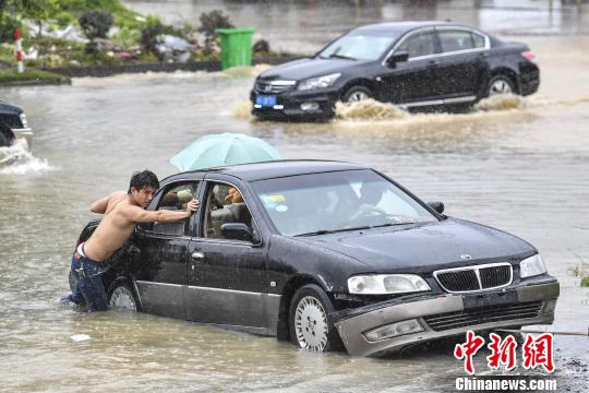 6月13日，惠州惠東縣新平大道上，市民在雨中推行拋錨的車輛。　陳驥旻 攝