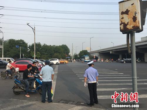 6月21日上午，北京仰山橋下十字路口，執(zhí)勤人員要求非機(jī)動車停在停止線后。湯琪 攝