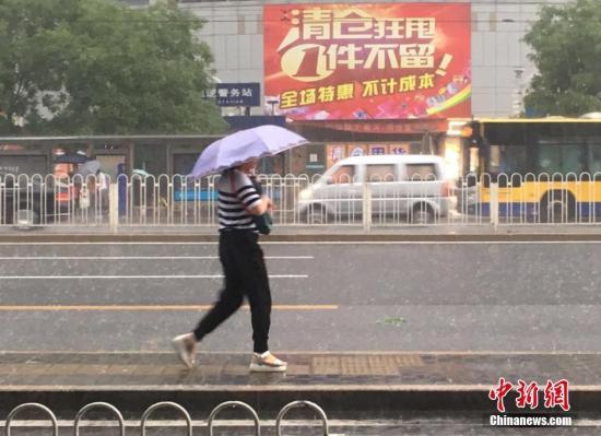 6月23日清晨，北京市民冒雨出行。 中新網記者 富宇 攝