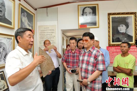 圖為趙文嶺(左)在影展上向馬本齋之子、海軍航空兵原副政委馬國超(右二)介紹影展中陳列的實物。　苑立偉 攝
