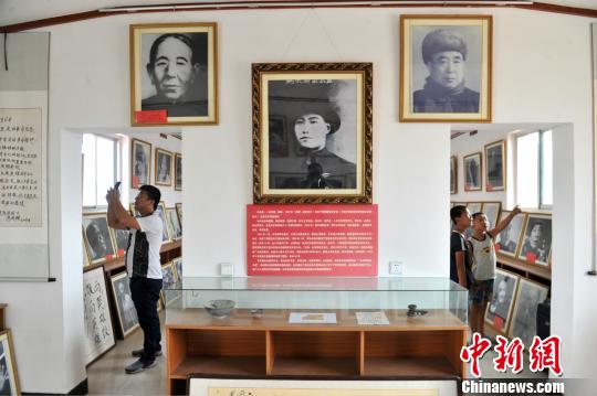 圖為群眾在趙文嶺家中參觀馬本齋與回民支隊事跡圖片展?！≡妨?攝