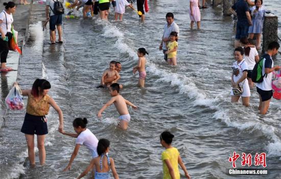 7月4日傍晚，市民們帶著小孩在海邊戲水消暑。連日來(lái)，受副熱帶高壓影響廈門(mén)地區(qū)持續(xù)高溫。 張斌 攝