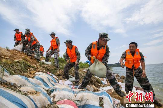 資料圖片，民兵應急分隊冒著酷熱進行堤壩加固。　傅建斌 攝