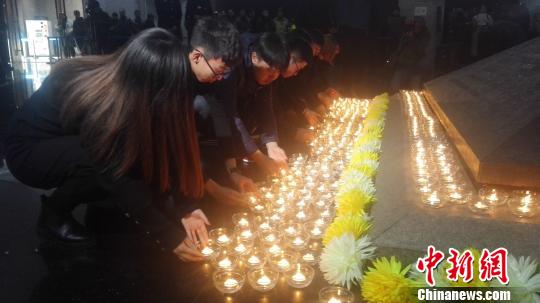 12月13日，沈陽“九一八”歷史博物館在國(guó)家公祭日舉行悼念儀式。圖為民眾向寓意民族英烈浩氣長(zhǎng)存的金字塔型臥碑敬獻(xiàn)燭火。　朱明宇 攝