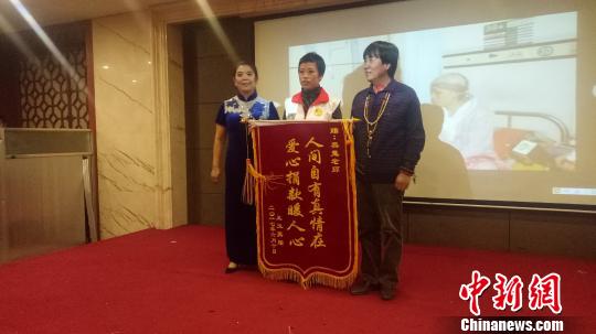圖為青海省抗癌協(xié)會癌癥康復(fù)工作委員會患癌病友王玉英為曾幫助他的書法家黑鬼送上錦旗。　張海雯　攝