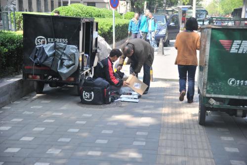 圖為快遞小哥在路邊配送快遞。呂春榮 攝