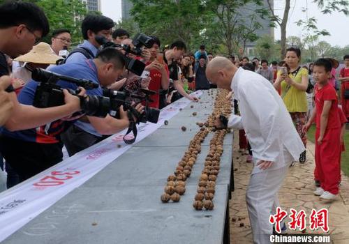 黎偉軍手劈核桃現場吸引不少人圍觀?！〕叹皞?攝