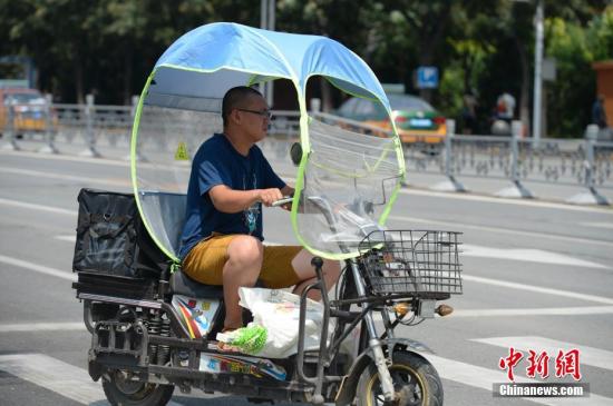 資料圖：男子在電動車上撐起遮陽棚。<a target='_blank' href='http://www.chinanews.com/'>中新社</a>記者 劉文華 攝