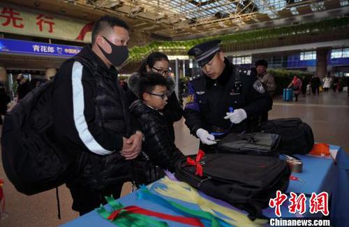 12月28日，北京西站派出所民警為背黑色雙肩包的旅客系上個性小標識，以防在通過安檢或乘車過程中出現(xiàn)錯拿情況。(完) 龐賀雷 攝