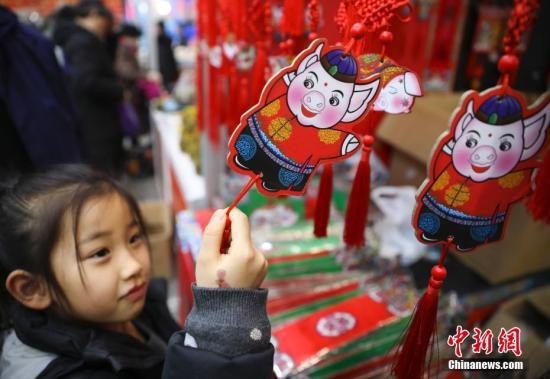 1月23日，正在北京全國農業展覽館舉辦的2019老北京年貨大集人頭攢動、熱鬧非凡。全國各地區優質特色產品及民俗文化在此一一呈現，給北京市民帶來精彩紛呈的購物體驗。圖為小女孩被年貨大集上的豬年福牌吸引。<a target='_blank' href='http://www.chinanews.com/'>中新社</a>記者 趙雋 攝