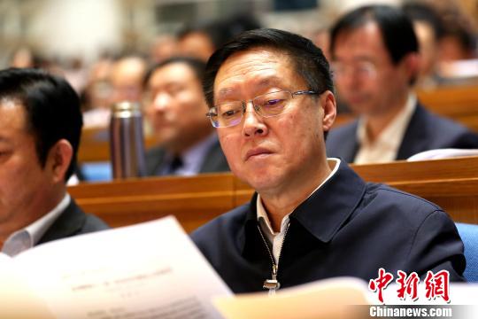 圖為與會政協(xié)委員在現(xiàn)場閱讀會議文件。　梁犇 攝