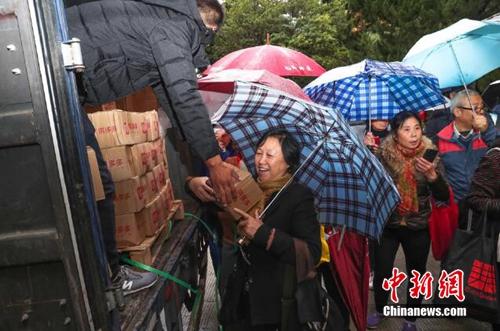 資料圖：上海百名居民在雨中排成一條長龍，領(lǐng)取剛到貨的秭歸臍橙。供圖