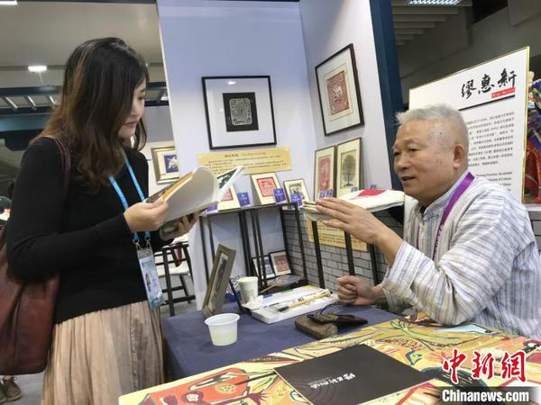 秀洲農民畫畫家繆惠新和參觀者交流。供圖